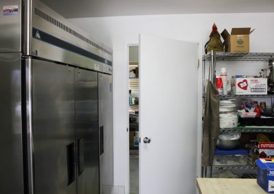 A view of the industrial refrigerator, rear of the kitchen, and entrance into the storage room, High Desert Hall, Hesperia, CA.